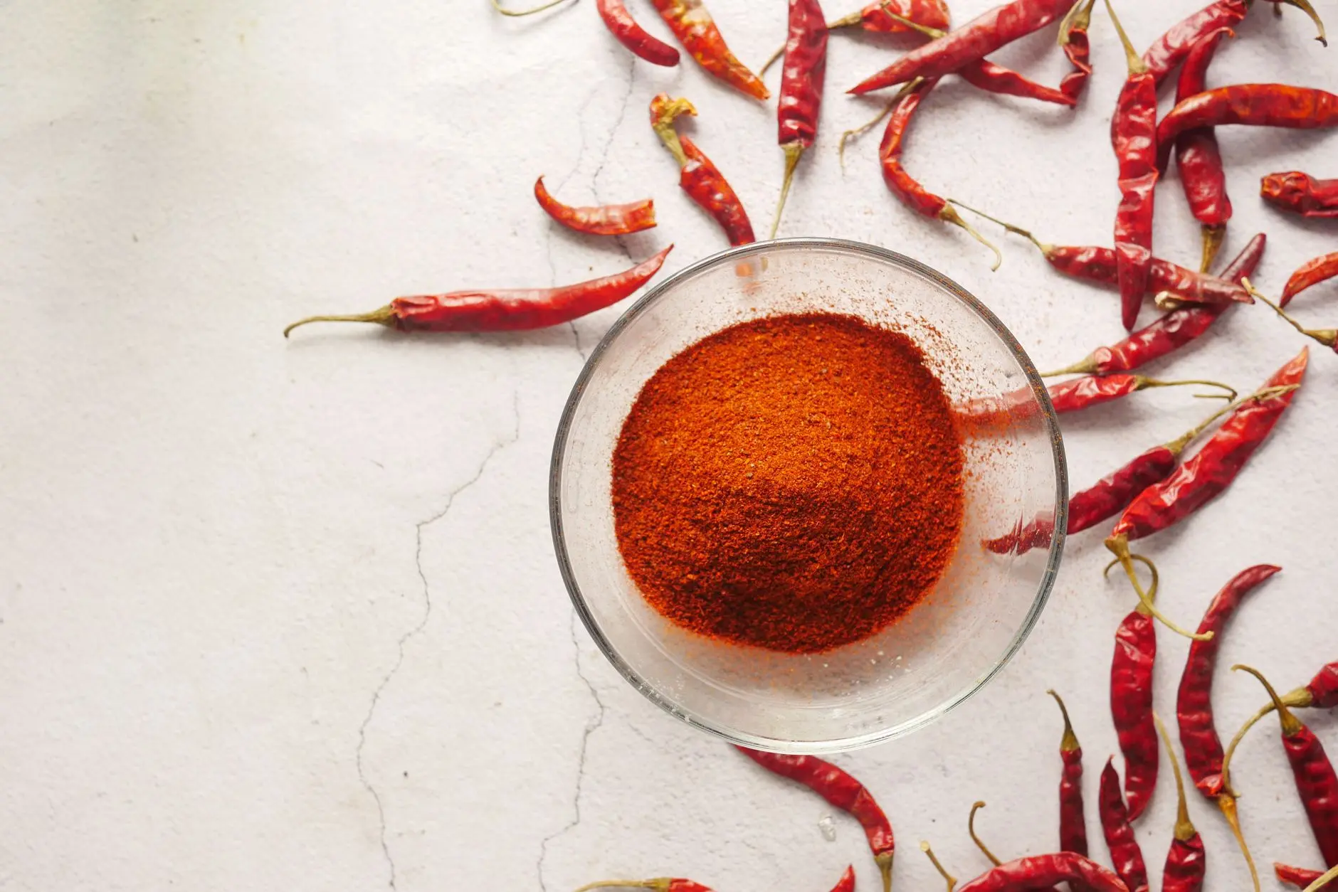 profile shot of bowl with bright red chilli powder and chillies
