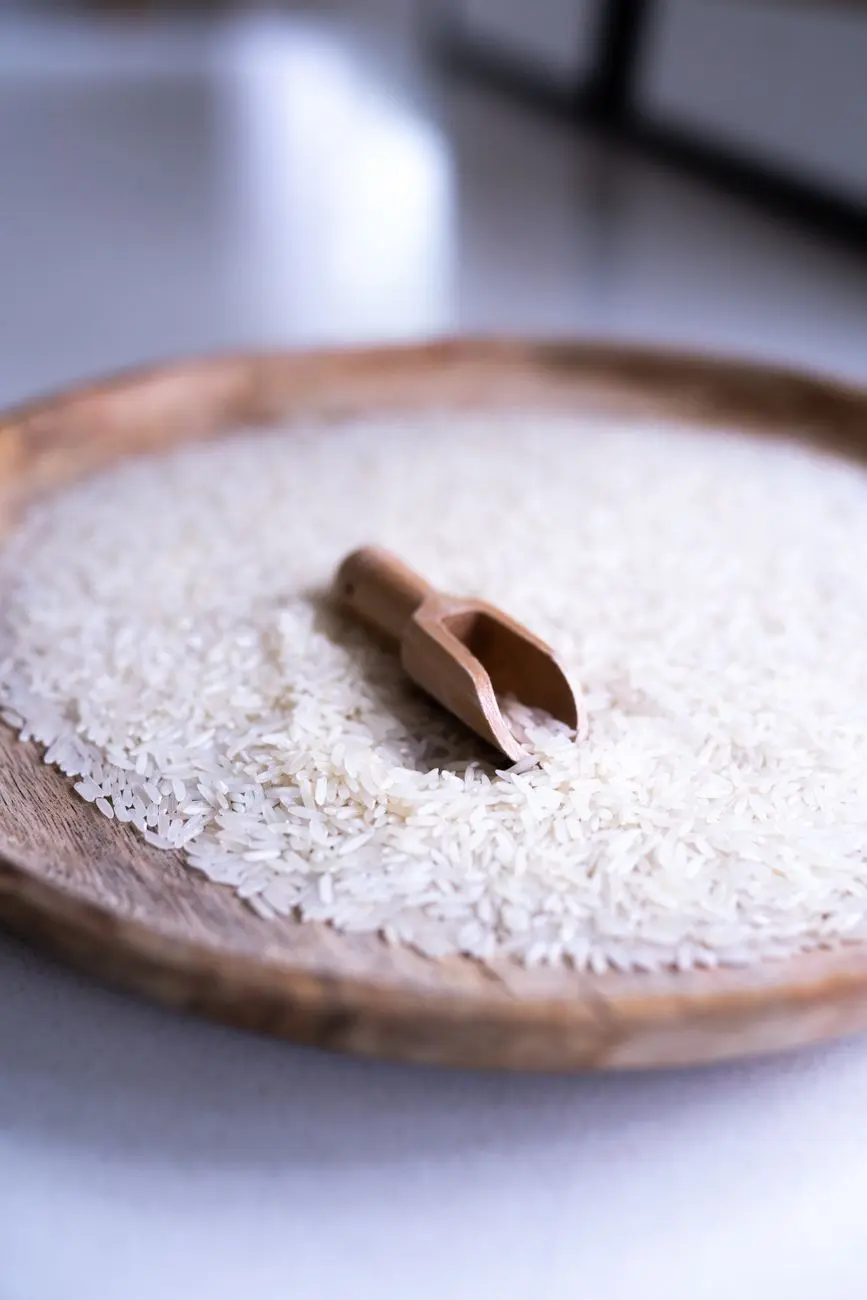 wooden plate with scoop, rice heap, soft background